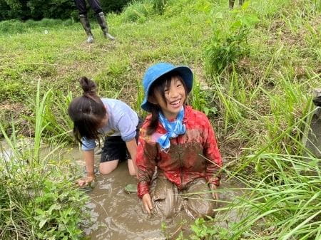 泥んこになりながら笑顔で田植え