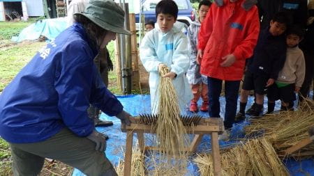 講師の方と一緒に千歯こきを使う子